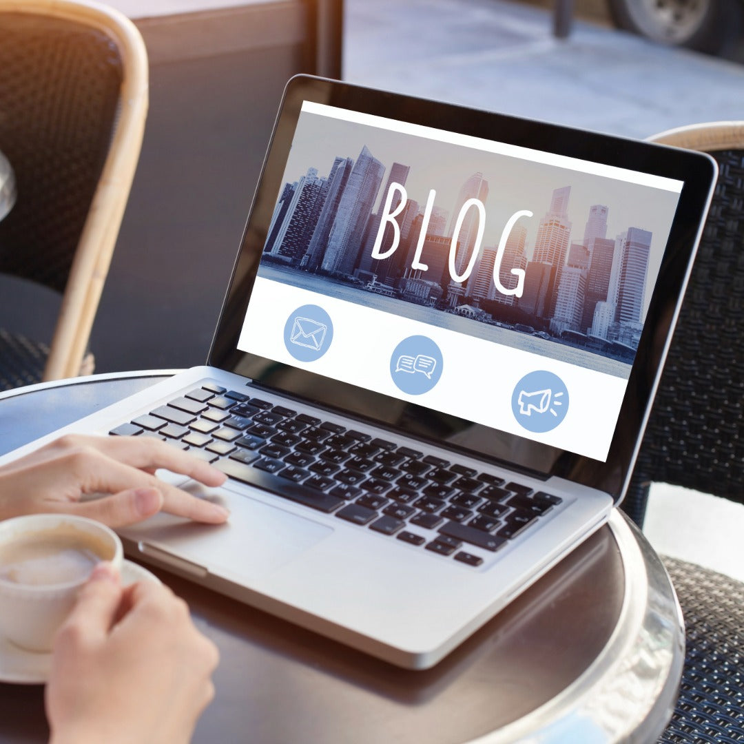 Person using a laptop with a blog-themed screen on a table with a cup of coffee.