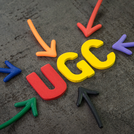 Colourful UGC, User Generated Content, with arrows pointing towards it on a dark textured background