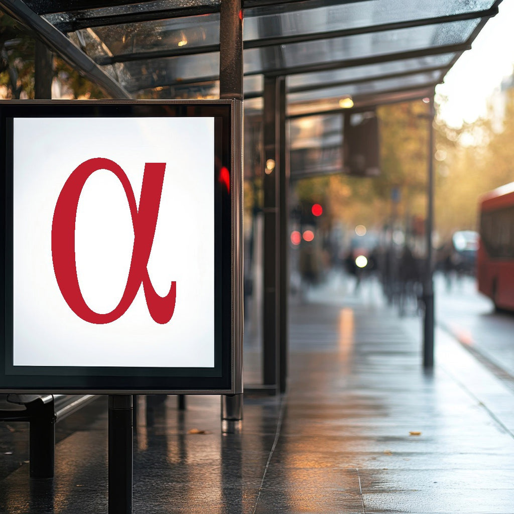 Red 'alpha' logo on a bus stop sign with a blurred city street background. Programmatic DOOH for SMEs | Hyper-Local Digital Billboards